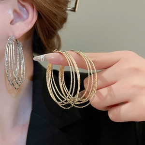 Detail of layered gold and silver hoop earrings with textured finish on model