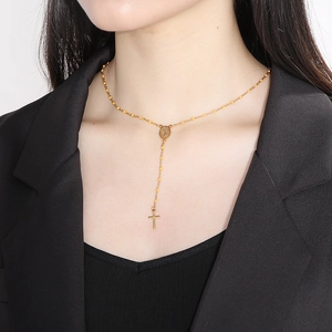 Detail of gold Y-necklace with orange beads, religious icon medal, and cross pendant