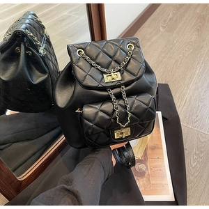 Detail of black quilted leather backpack with gold chain straps and metal twist locks