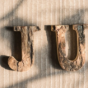 Close-up of rustic wooden capital letters with natural bark texture for vintage DIY decor