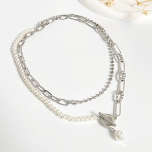 Detail of layered silver metal and pearl necklace with T-bar clasp on white background
