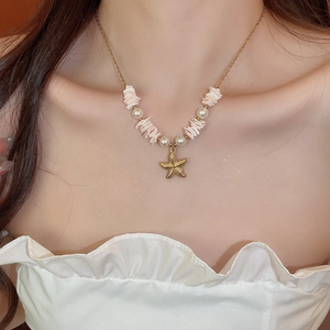 Detail of starfish pendant necklace with pearls and shell pieces on a delicate gold chain