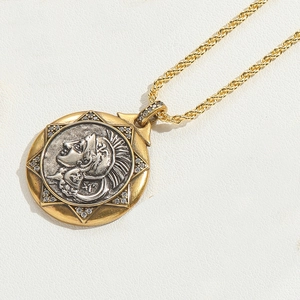 Detail of vintage coin pendant necklace with gold chain and silver relief carving