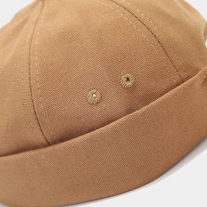 Detailed close-up of brown canvas docker hat featuring embroidery eyelets and stitching