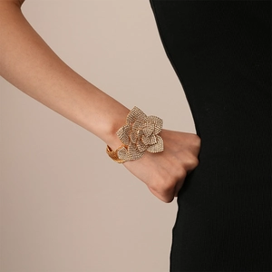 Detail of a large gold flower cuff bracelet with rhinestones worn by a model