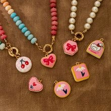Detailed flat lay of beaded pearl necklaces with colorful cherry and daisy charms