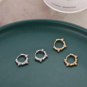 Micro-pave zircon geometric hoop earrings in gold and silver finish on a green tray