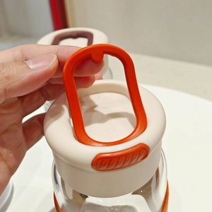 Detail showing an orange silicone carry handle on a clear glass water bottle cap