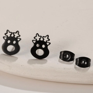 Macro detail of matte black reindeer stud earrings with butterfly backs on beige tray