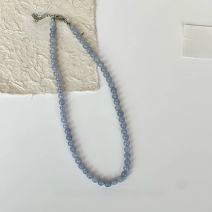 Mise à plat d'un collier de perles bleu aigue-marine avec fermoir mousqueton argenté