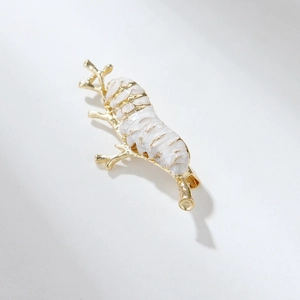 Macro shot of white enamel cicada insect brooch with gold-tone wing details and branch