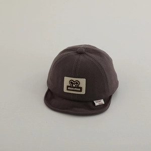 Dettaglio del cappellino in cotone beige scuro per neonati con orecchie e tesa morbida