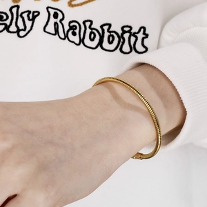 Close-up of 18K gold snake bone chain bracelet featuring tight metallic ring texture