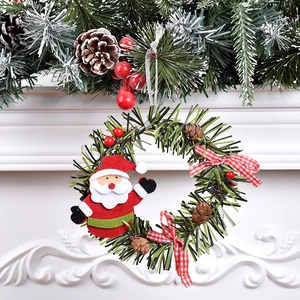 Christmas wreath ornament with Santa doll, pine cones and red checkered bow on white fireplace