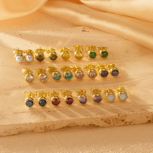 Vue macro de boucles d'oreilles en acier inoxydable et zircons sur tissu en soie chic