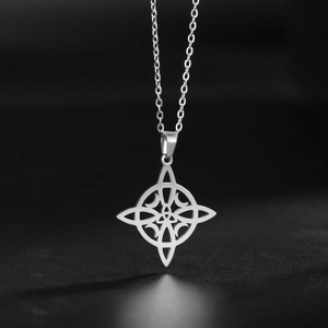 Gros plan du pendentif nœud celtique argenté avec des ombres sur une surface noire