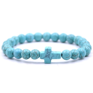 Macro view of turquoise beads bracelet featuring a central cross charm on white background