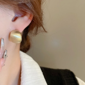Close-up of a gold brushed C-shaped hoop earring on model with matte finish
