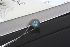 Macro shot of S925 silver necklace with blue moonstone pendant on reflective base