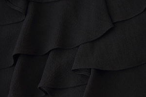 Macro shot of black chiffon fabric texture with layered ruffle design details