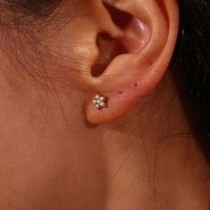 Gros plan de boucles d'oreilles fleur plaquées or 18 carats avec perles sur le modèle