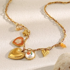 Vue détaillée des pendentifs cœur et fleur plaqués or 18K sur une chaîne trombone