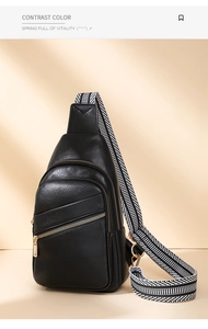 Detail of black pebbled leather chest bag with striped wide strap and gold hardware