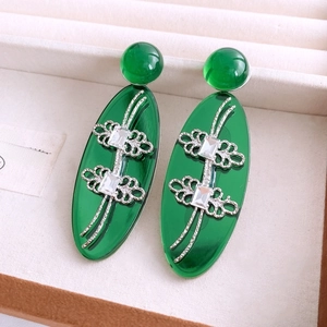 Détail de boucles d'oreilles vintage en résine verte avec motifs floraux argentés en boîte