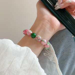 Detailed shot of a gold-plated beaded bracelet with green and pink gradient glass beads