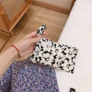 Gros plan détaillé d'une pochette en tissu à fleurs noires et blanches avec fermeture