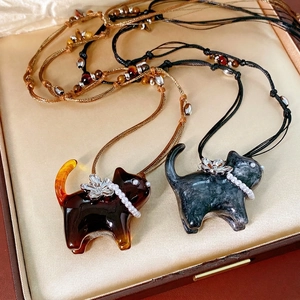 Cat flower pendant necklace with pearls and woven cord displayed on champagne silk
