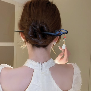 Detail view of a vintage wooden hairpin with tassels and enamel beads on a bun hairstyle