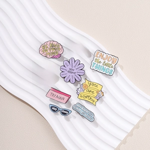 Set of colorful enamel pins with motivational English phrases on white texture