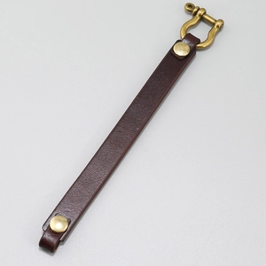 Detail of dark brown leather bracelet with brass horseshoe clasp on grey background