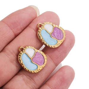 Pendentifs haricots dorés avec émail blanc et bleu, vue rapprochée à la main