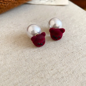Détail macro de boucles d'oreilles ours floqué rouge avec fermoirs perles blanches