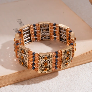 Detail of vintage gold bracelet with amber and blue beads placed on a book