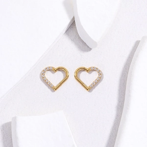 Detail of 16G gold heart-shaped titanium hinged earrings set with shimmering cubic zirconia