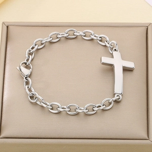 Detailed close-up of a silver stainless steel cross pendant on an O-chain bracelet