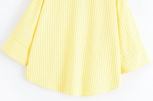 Detailed view of the yellow and white striped shirt featuring the curved hem and sleeve cuffs