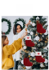 Close-up of red cable-knit Christmas stockings with white embroidered cuffs on a tree