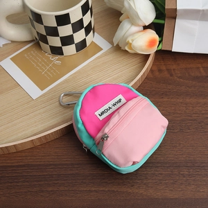 Mini pink nylon backpack pouch with silver carabiner shown on wooden surface with decor