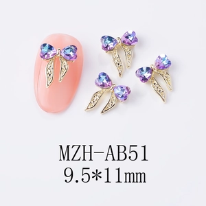 Vue macro d'un bijou d'ongle nœud doré 9,5x11mm avec strass cœur violet et bleu