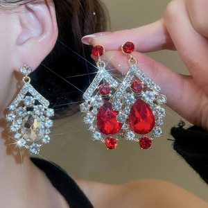Close-up of vintage drop earrings with red and clear crystals worn by a model