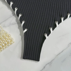 Close-up of black ribbed one-piece swimwear featuring side lacing and metal eyelet details