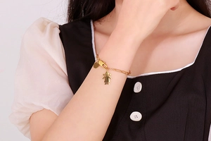 Détail d'un bracelet en titane doré avec pendentif silhouette de fille sur le poignet