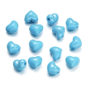 Flat lay of blue heart-shaped DIY craft beads for jewelry making on white background