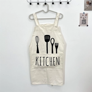 Detail view of cotton linen kitchen apron with large front pocket and utensil print