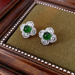 Detailed macro of floral silver stud earrings with a green center stone and crystals