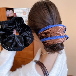 Detailed view of large velvet flower scrunchies with lace trim in black and brown colors